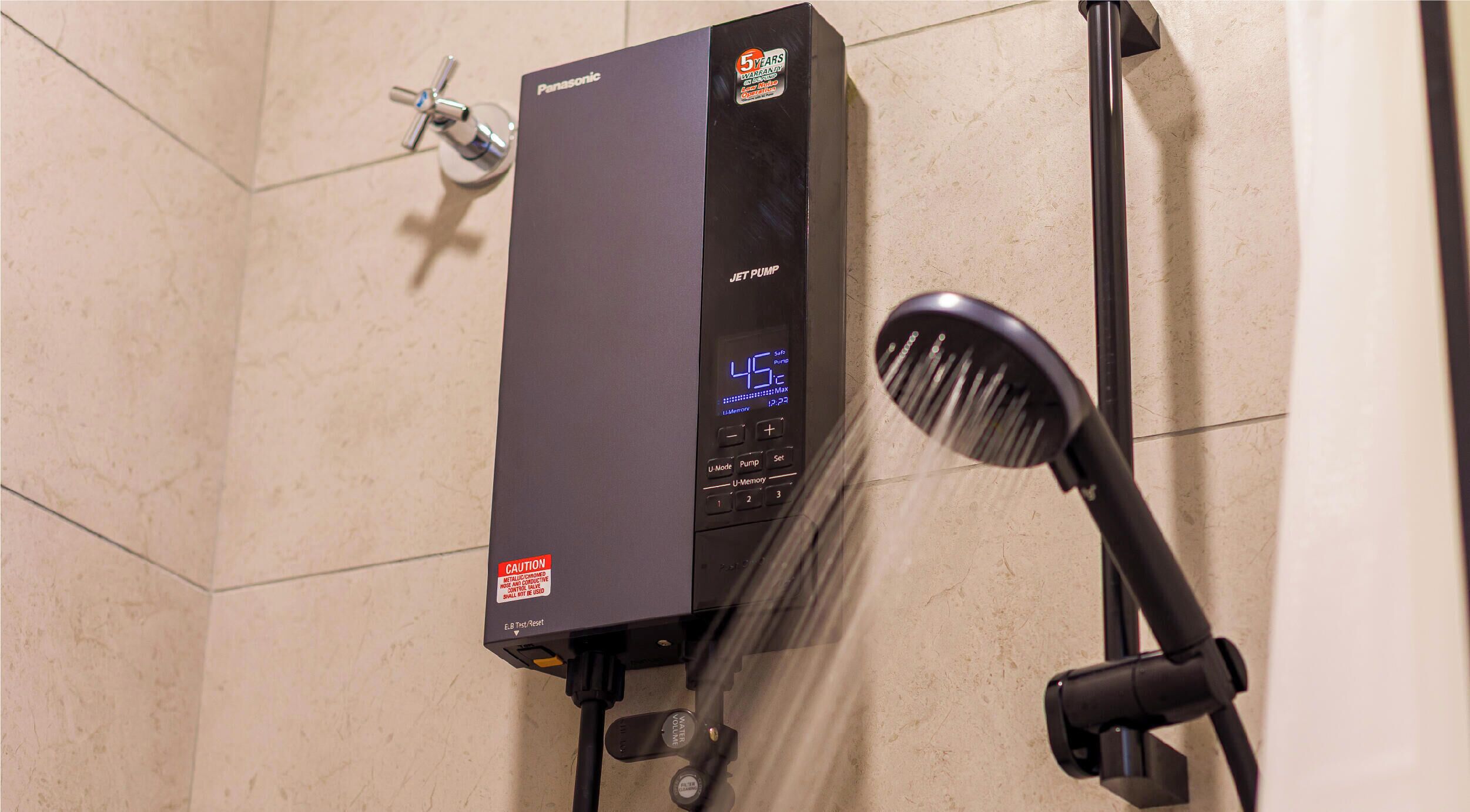 Une salle de bain avec un chauffe-eau noir, un écran numérique et une pomme de douche.