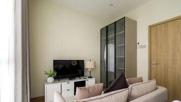 A modern living room with a flat-screen TV, a white cabinet, a sofa, and a wooden door.