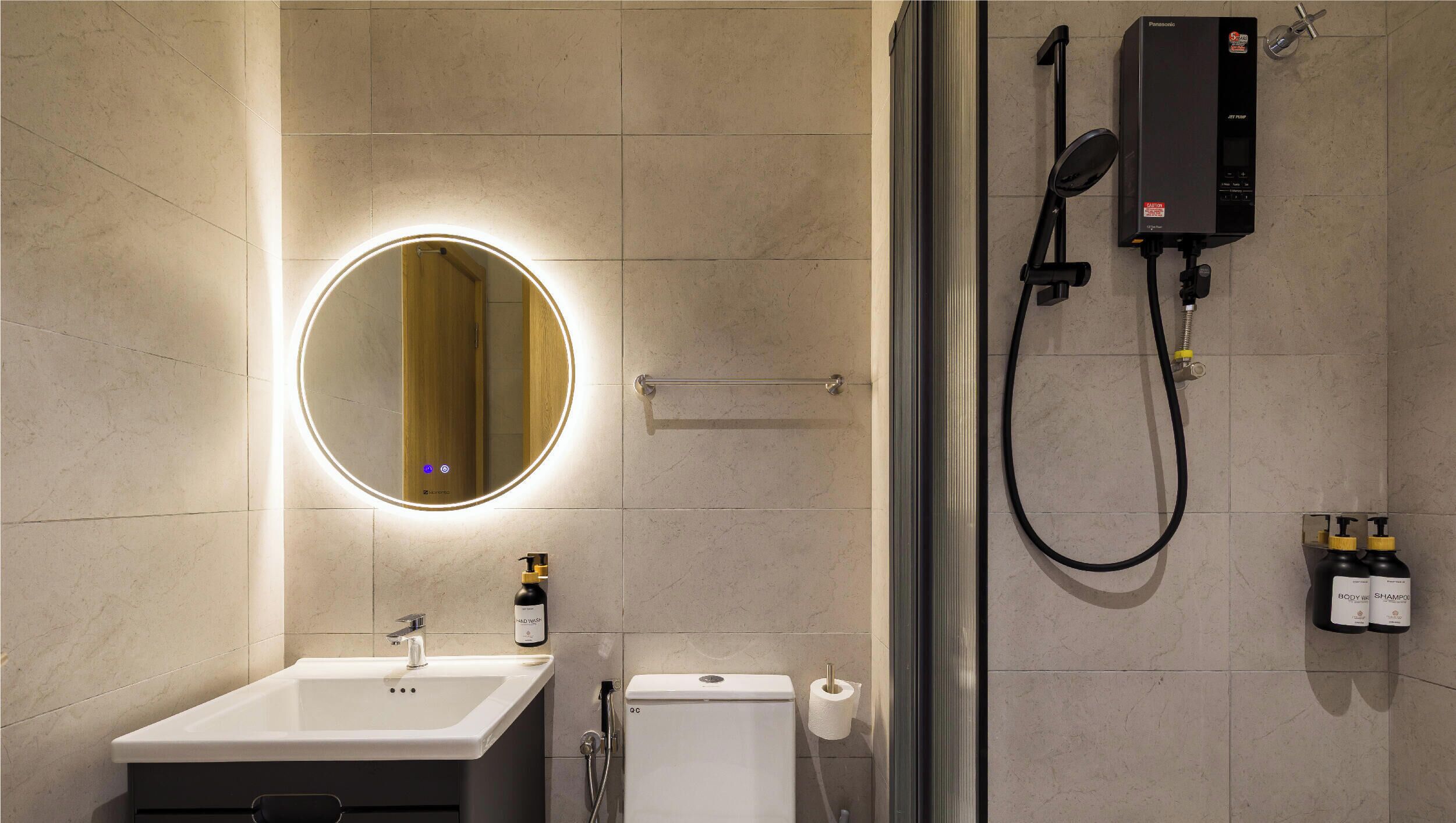 Un baño moderno con un espejo redondo, un lavamanos, un inodoro y una ducha.