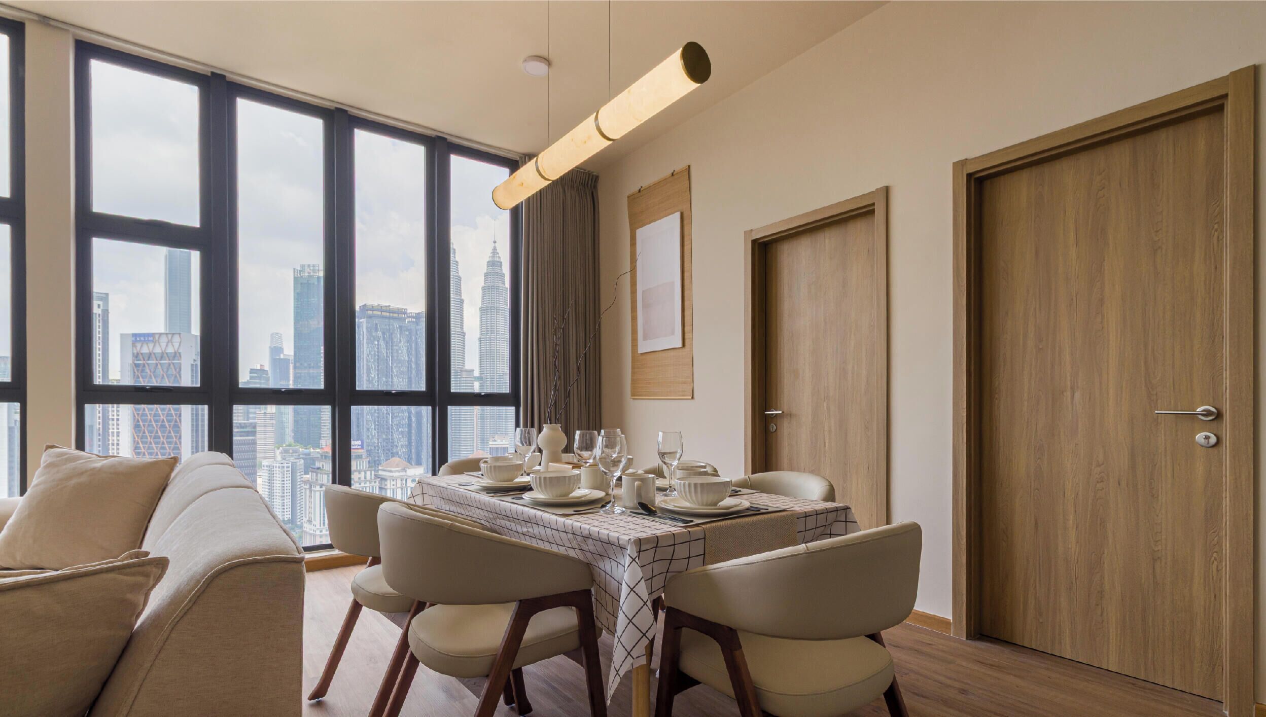 A dining area with a table set for four, large windows with a city view, and a wooden door.