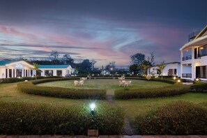 A landscaped garden with seating areas and a pathway leading to a building. - Baris resort Corbett (Ramnagar)