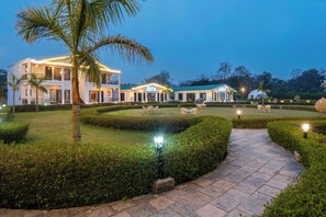 A well-lit resort with a pathway, manicured gardens, and multiple buildings including a dome structure. - Baris resort Corbett (Ramnagar)