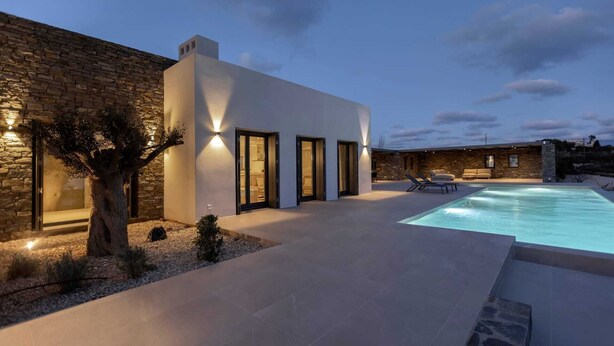 A modern house with a swimming pool, stone walls, and a well-lit exterior. - Celestial II             ., Villa (Paros)