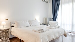 Un lit bien fait, avec du linge de lit blanc, une lampe de chevet et une table de chevet avec une autre lampe.