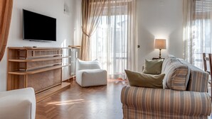 Un salon moderne avec un téléviseur à écran plat, un canapé, un fauteuil et une console en bois.