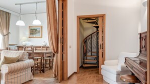 Un salon comprenant un canapé, un piano, un escalier et un coin repas avec une table et des chaises.