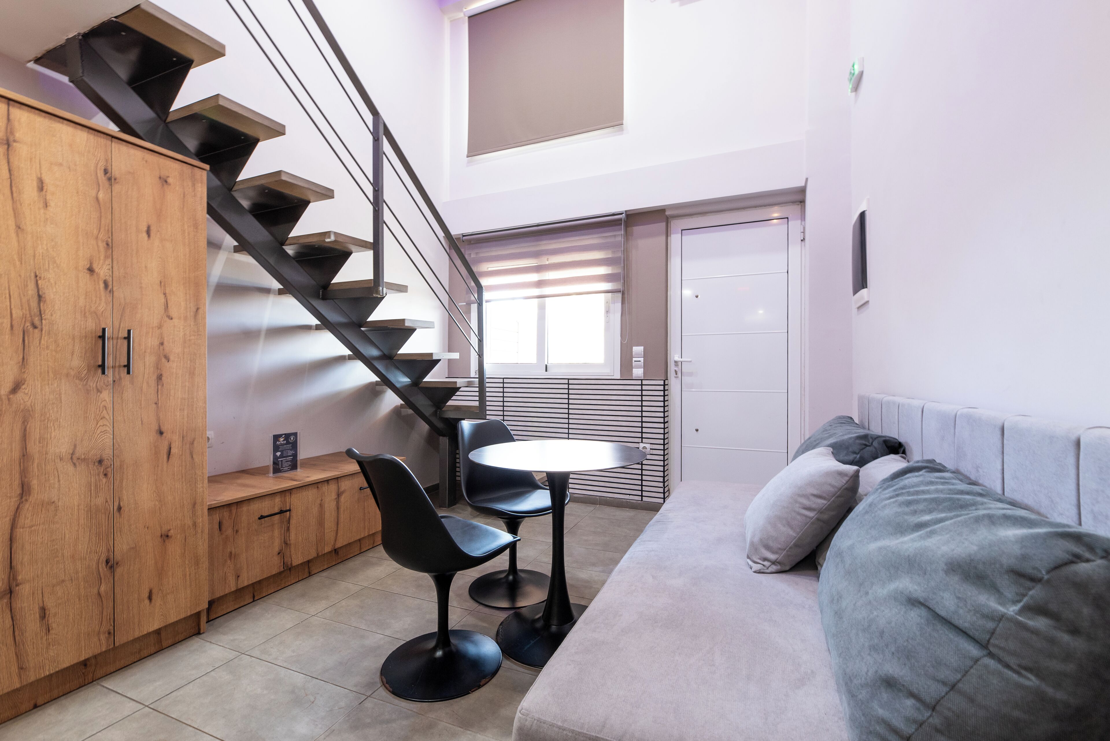 A modern living space with a staircase, a sofa, a small table, and a wooden cabinet.
