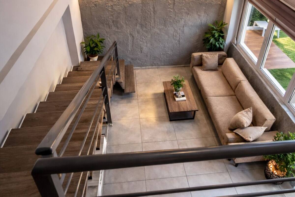 A modern living room with a staircase, a sofa, a coffee table, and a decorative wall piece.