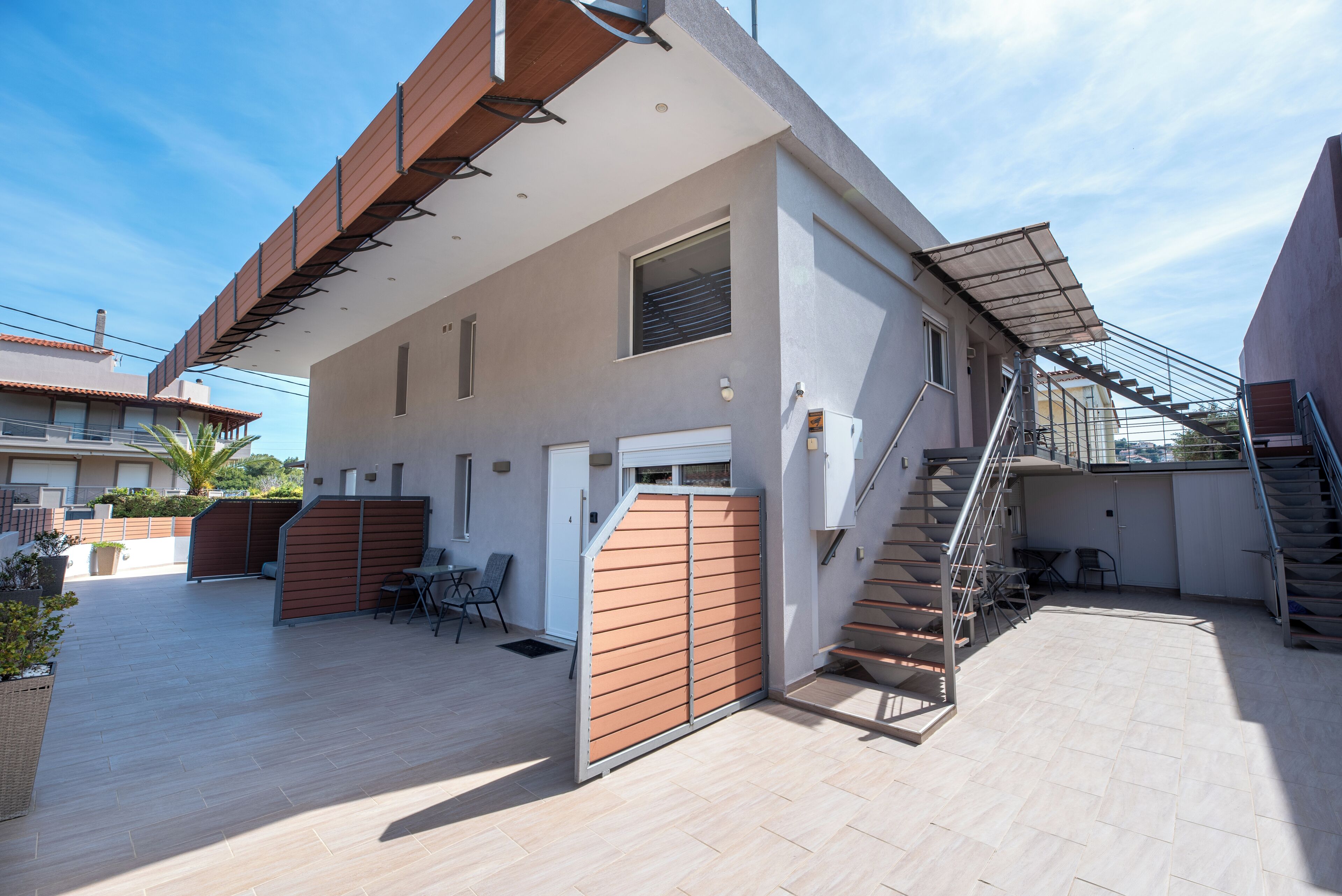 A modern building with a staircase, a covered outdoor seating area, and a view of the surrounding neighborhood.