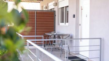 A balcony with a metal railing, a table, and two wicker chairs.