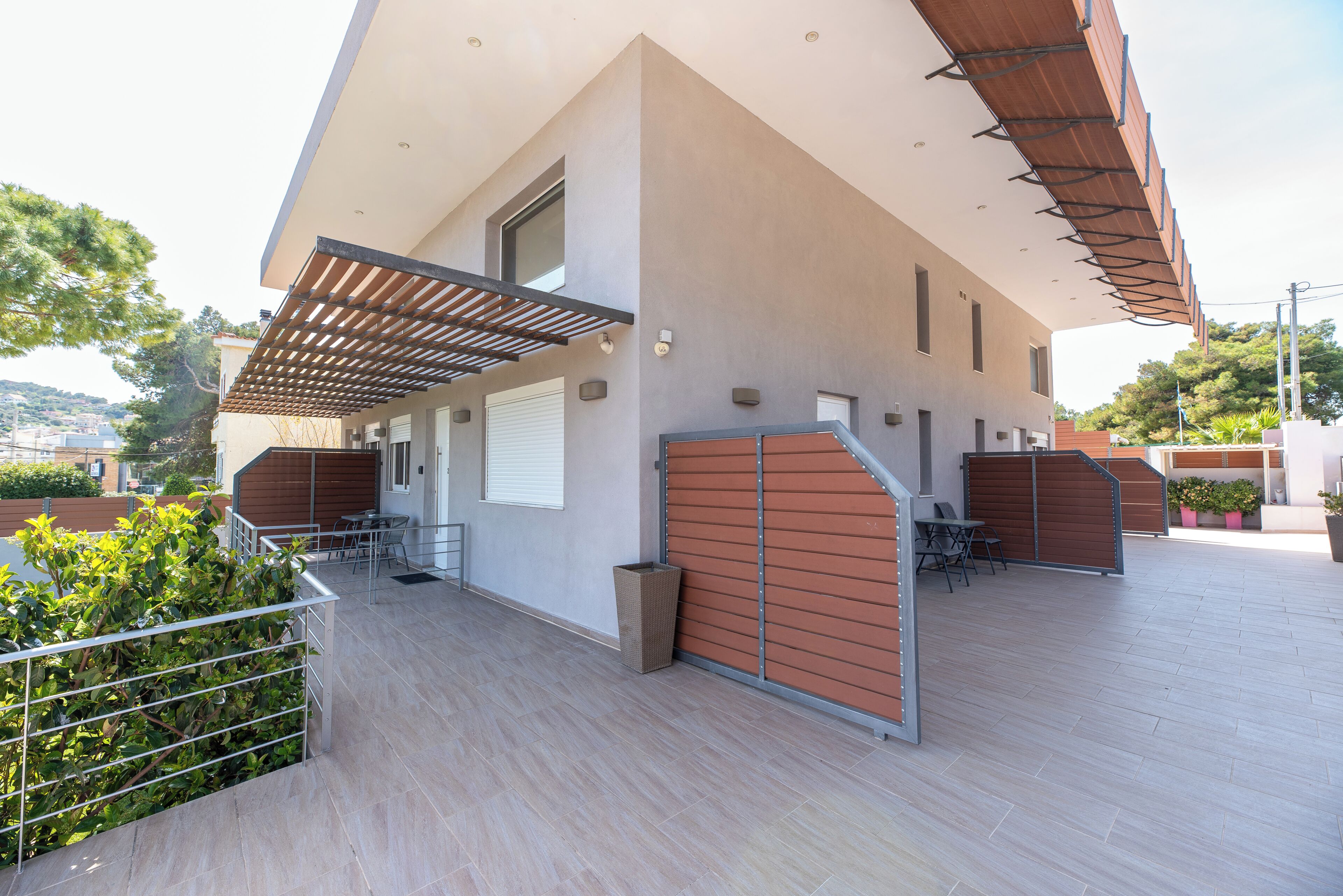 Un bâtiment moderne doté d’un patio couvert, d’un espace extérieur aménagé pour s’asseoir et offrant une vue sur le paysage environnant.