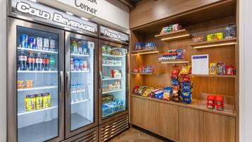 A cold beverage and frozen food vending area with snacks and a menu sign.