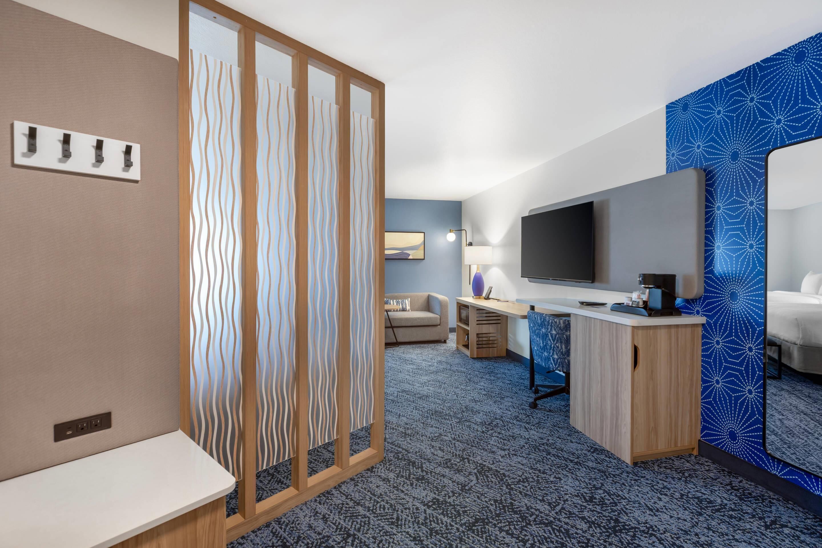Habitación de hotel con escritorio, televisor, sofá y cama.