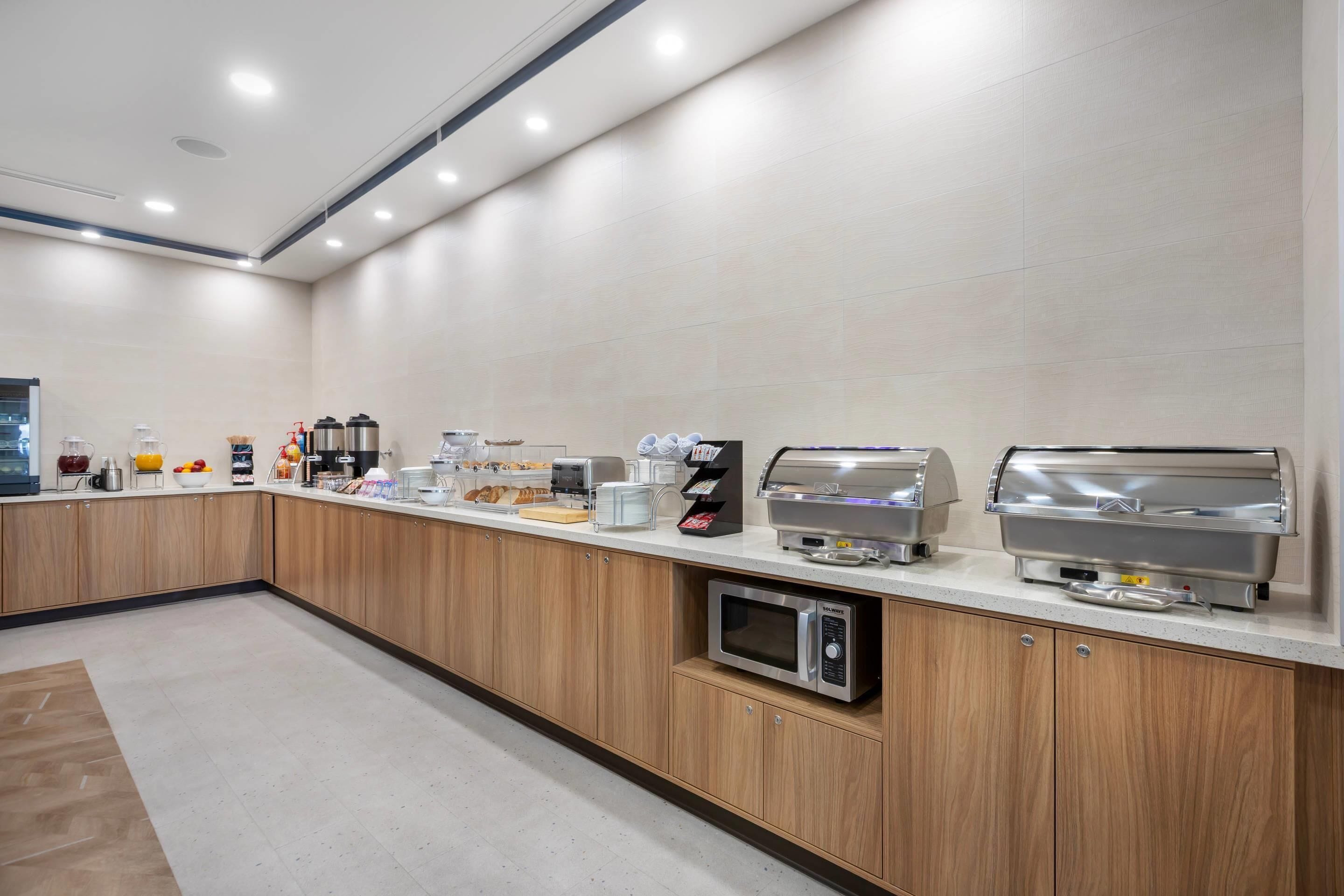 Una cocina moderna con una barra alargada, equipada con cafeteras, microondas y tostadora.