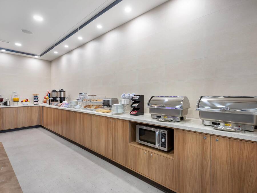 A modern kitchen area with a long counter, equipped with coffee makers, a microwave, and a toaster.