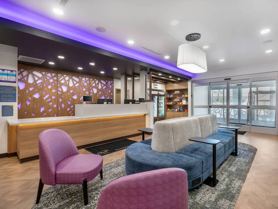 A hotel reception area with a modern design, featuring a reception desk, seating area with armchairs, and a large window providing a view.