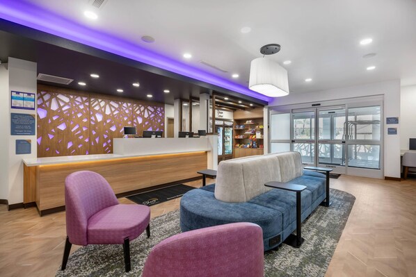 A hotel reception area with a modern design, featuring a reception desk, seating area with armchairs, and a large window providing a view. - Sleep Inn & Suites Henderson – Las Vegas (Henderson)