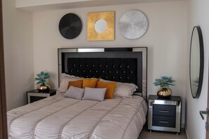 Quarto com uma cama, duas mesas de cabeceira, um penteado e três quadros na parede.