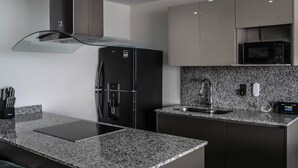 Ett modernt kök med bänkskivor i granit, rostfria vitvaror och en inbyggd mikrovågsugn.