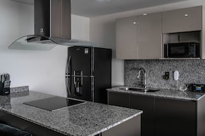 A modern kitchen with granite countertops, stainless steel appliances, and a built-in microwave. - Sunny Horizon (Mazatlán)