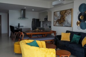 Uma sala de estar moderna com um sofá amarelo, um sofá escuro e uma mesa de centro de madeira.