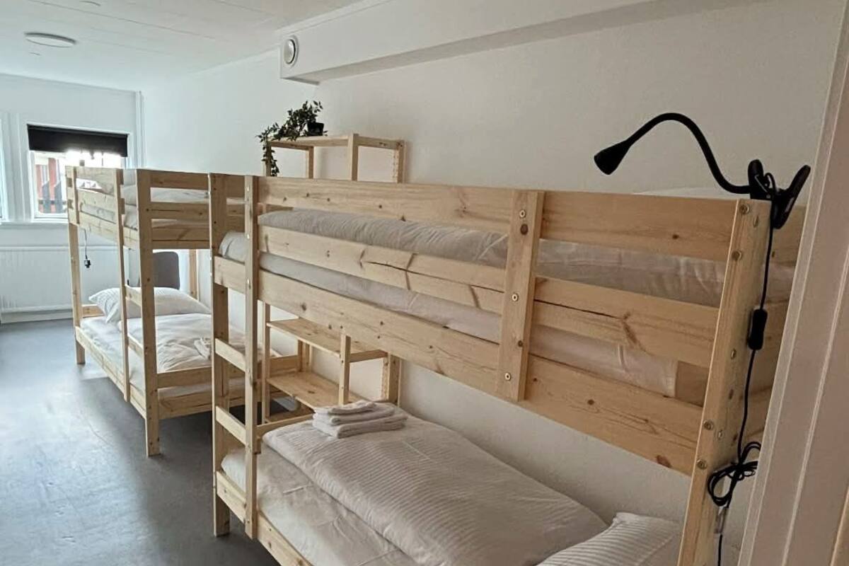 Une chambre avec un lit superposé, une tête de lit en bois, une échelle et une prise électrique au mur.