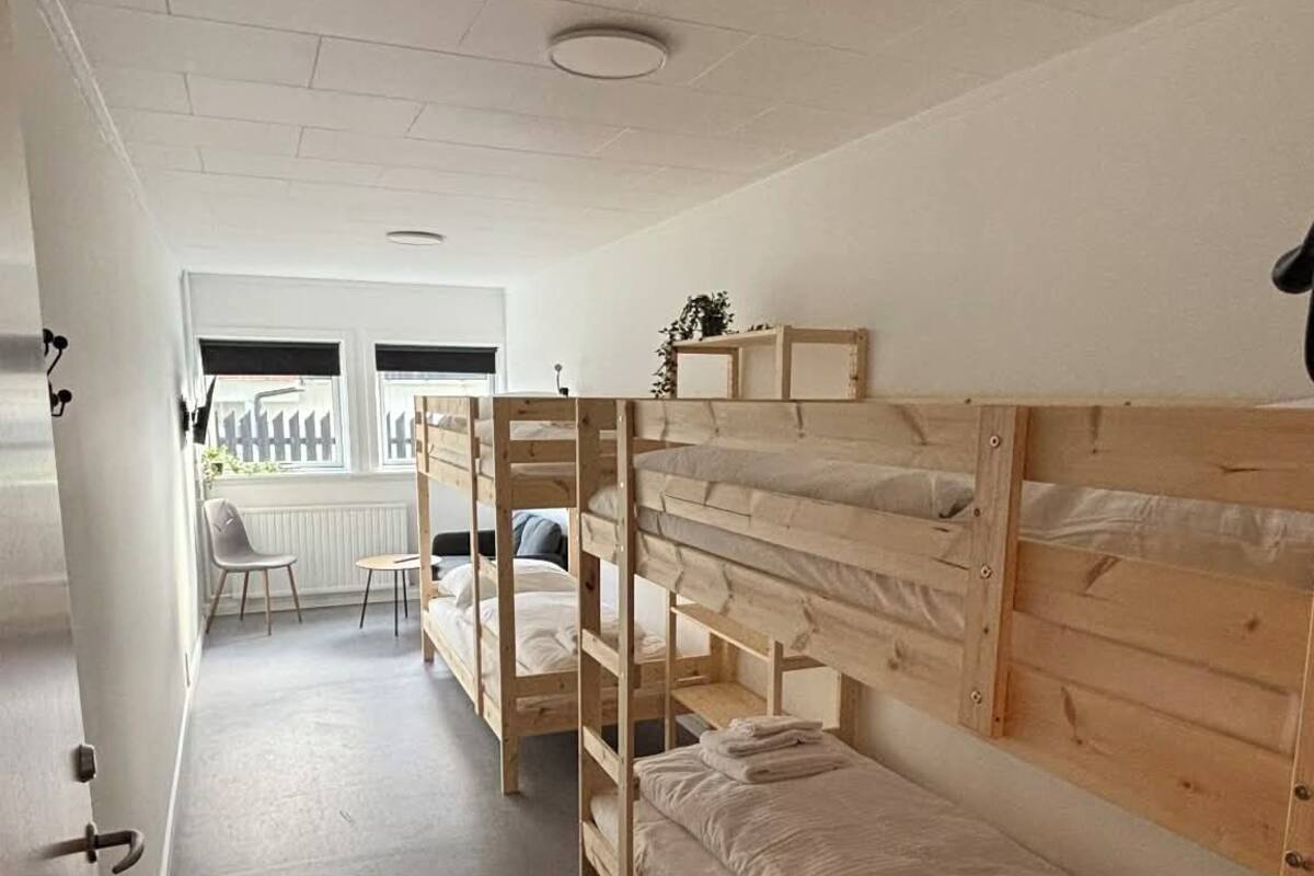 Une chambre de dortoir avec des lits superposés, une petite table et une chaise.