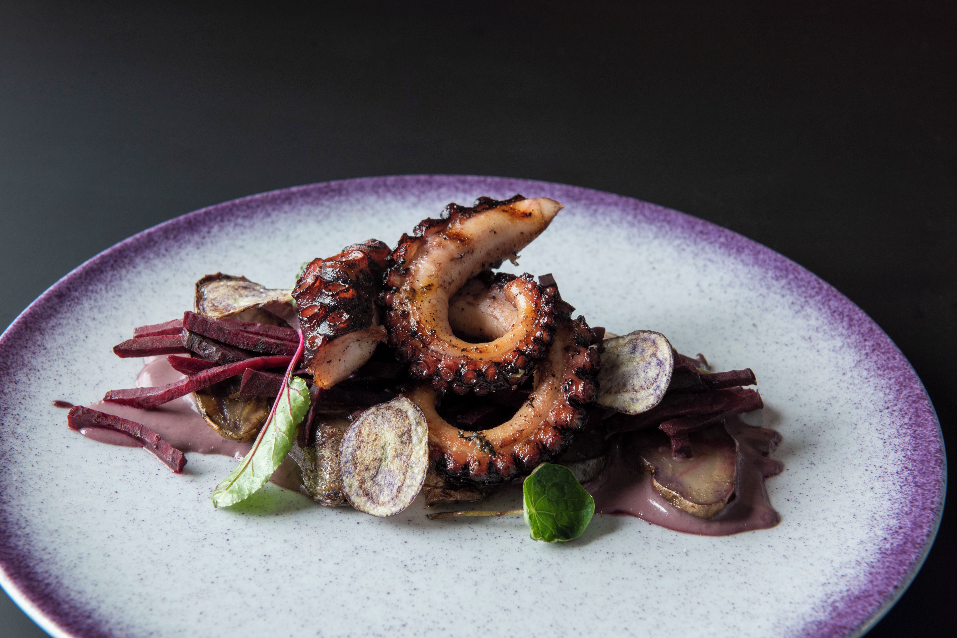 A plate of food with octopus and greens.