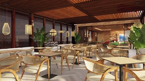 A modern indoor seating area with wooden tables and chairs, large windows with blinds, and hanging light fixtures. - Hotel Nodo (Santiago)
