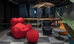 A modern interior with a long table, multiple chairs, and unique red and black seating. - Hotel Nodo (Santiago)