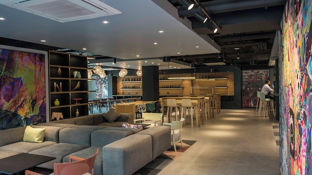A modern interior with a sectional sofa, dining area, and artwork. - Hotel Nodo (Santiago)