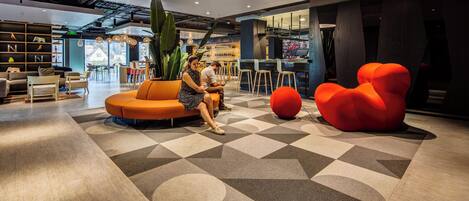 A modern interior with a seating area, a large plant, and a unique red chair.