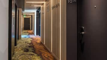 A hotel hallway with lockers, a carpeted floor, and a door labeled '106'.
