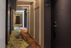 A hotel hallway with lockers, a carpeted floor, and a door labeled '106'. - Hotel Nodo (Santiago)