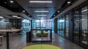 An office space with glass walls, a central seating area, and a modern ceiling design. - Hotel Nodo (Santiago)