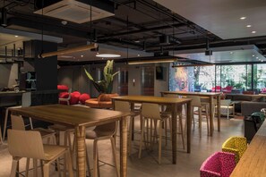 Un interior moderno con mesas y sillas de madera, una zona de bar y un ventanal con vistas.