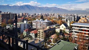 A cityscape with buildings, a church, and mountains in the background. - Hotel Nodo (Santiago)