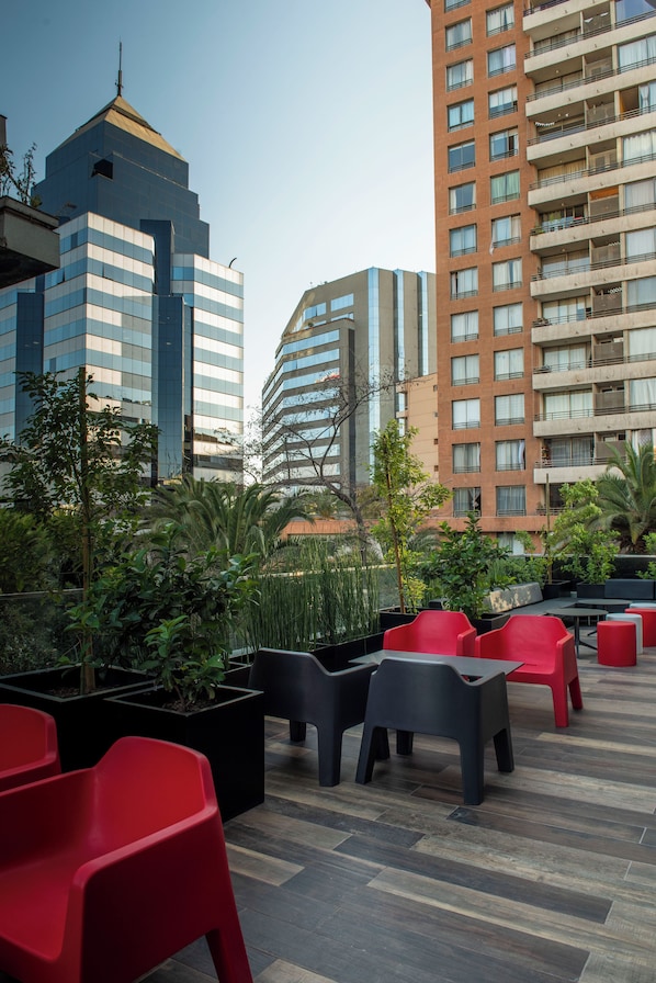 A rooftop terrace with outdoor seating, potted plants, and views of surrounding buildings. - Hotel Nodo (Santiago)