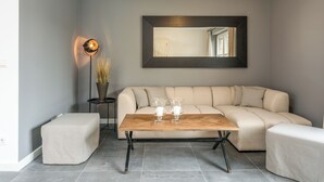 Een moderne woonkamer met een beige modulaire bank, een houten salontafel en een vloerlamp.