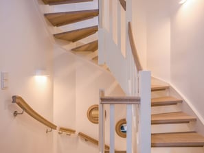 A wooden staircase with white railings and a wall-mounted light fixture.