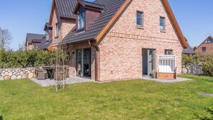Una casa a due piani con facciata in mattoni, tetto spiovente e porta garage.