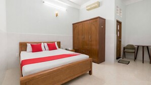 Ein Hotelzimmer mit einem hölzernen Bett, einem Kleiderschrank, einem Schreibtisch und einem Stuhl.