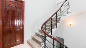 Eine Holztür mit Messingschild, eine Treppe mit hölzernem Geländer und eine Wandleuchte.