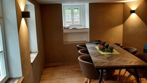A dining area with a long wooden table, six chairs, and a window with a view of greenery. - Historic vacation home in Bacharach with parking space (Bacharach)