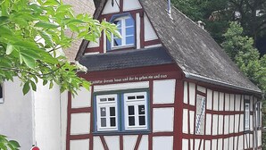 A traditional half-timbered house with a steeply pitched roof, a visible chimney, and a small window with a blue frame. - Historic vacation home in Bacharach with parking space (Bacharach)