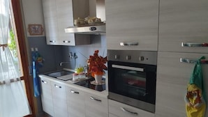 Eine moderne Küche mit hellen Holzschränken, einem Edelstahlbackofen und einer Spüle.