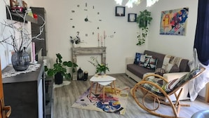 Ein Wohnzimmer mit Kamin, einer Couch, einem Schaukelstuhl und einer Wanduhr.