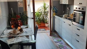 Eine kompakte Küche mit Essbereich, mit Fliesenboden, einem kleinen Esstisch und Stühlen sowie einem Kühlschrank.