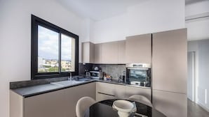 Una cocina moderna con un ventanal grande, una mesa de comedor con sillas y electrodomésticos integrados.