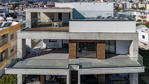 Un edificio moderno de varios pisos con zonas de estar al aire libre y barandillas de vidrio.